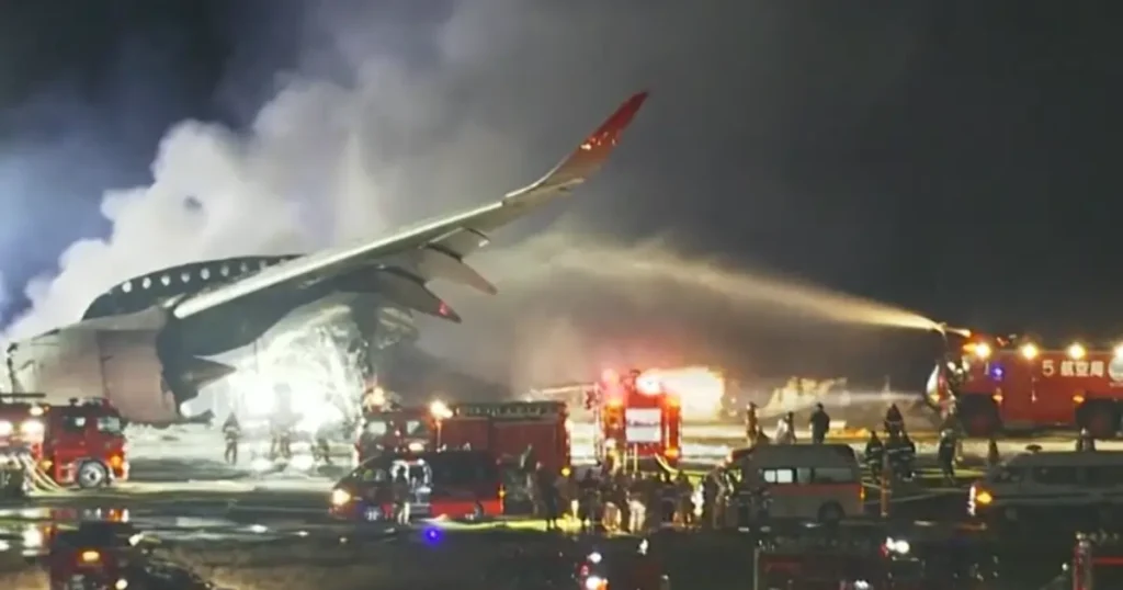 Firefighter hose spraying torrents of water and foam onto the burning aircraft